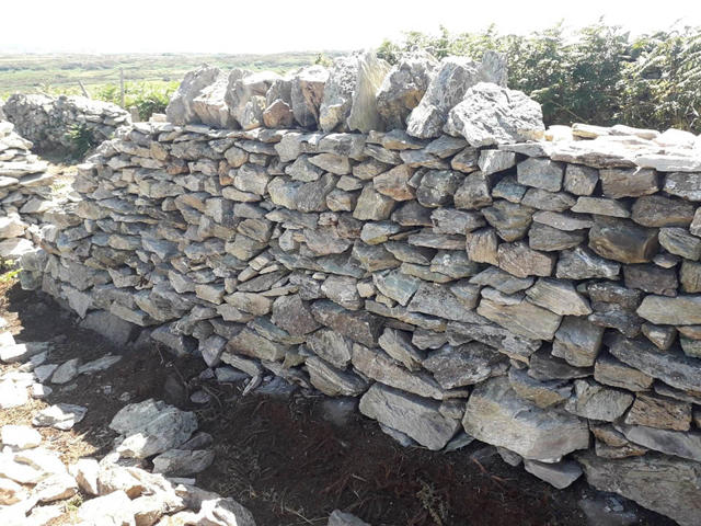 A completed section of the repaired wall with coping stones