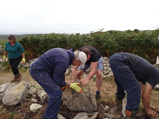 Volunteers laying large foundation stones before rebuilding