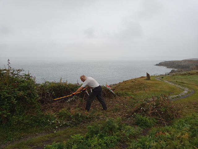 Volunteer removing overgrowth from the footpath