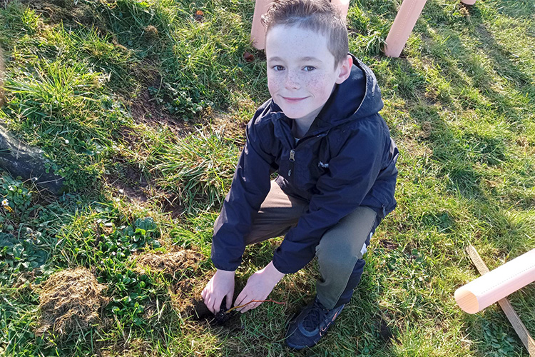 A young boy planting a tree.