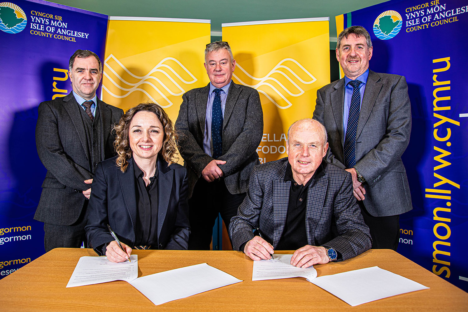 Photo shows Council Leader, Councillor Llinos Medi and Chairman of Grŵp Llandrillo Menai, Dr Griff Jones, signing the Memorandum of Understanding; joined by Anglesey Council Chief Executive, Dylan J Williams, Education portfolio holder, Councillor Ieuan W