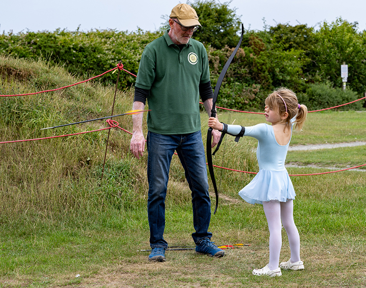 A gentleman teaching a child archery.