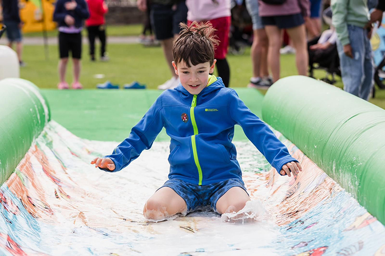 Young boy sliding down a water slide.