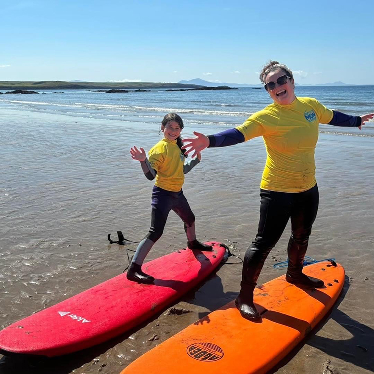Young girl and women standing on surf boards.